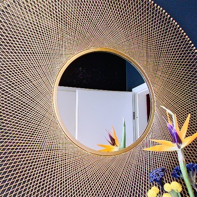 Gold sunburst mirror above a console with bird-of-paradise flowers