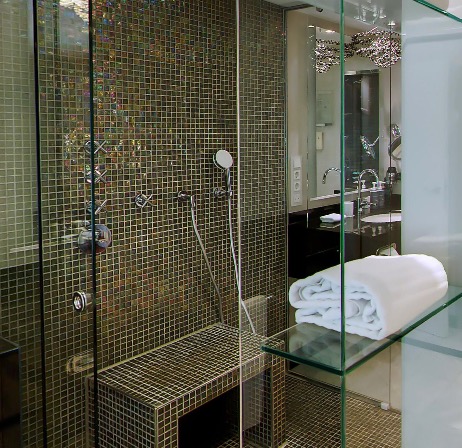 Glass-enclosed shower with mosaic tiling and rolled towel